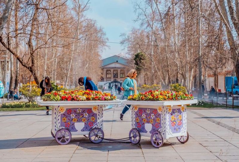 Fleurs colorés et habitants locaux sur une place - Iran | Au Tigre Vanillé