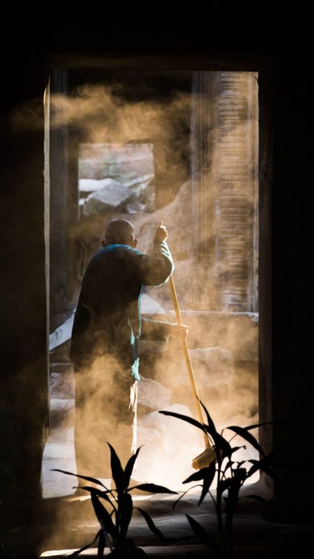 Un homme balaie la poussière dans la lueur du jour