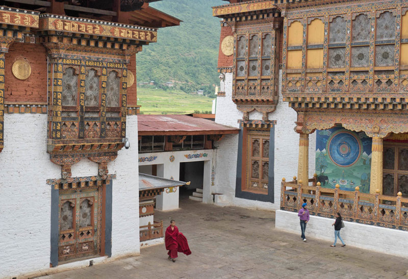 Bhoutan, cour d'un monastère avec un moine qui la traverse