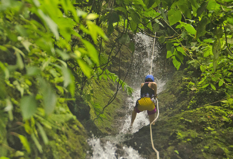 Costa Rica, une femme se laisse glisser en rappel le long d'une cascade