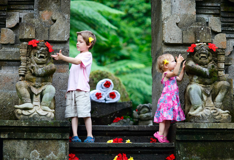 A Bali, Indonésie, deux enfants scrutent les statues d'un temple